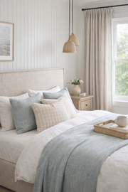 Bedhead and headboard with slipcover in a Cozy bedroom with a bed, pillows, and a side table with a lamp.